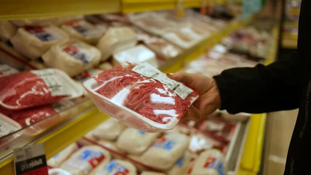 Customer holding a package of ground meat at the grocery store.