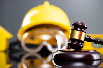 Construction law concept. Helmet and judge’s gavel on the gray background.