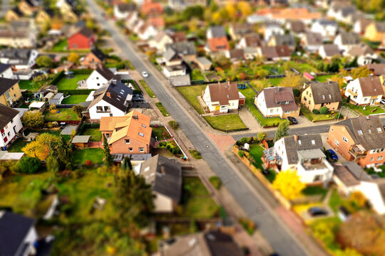 Suburb with family houses, front gardens and afterban, aerial view with tilt shift effect