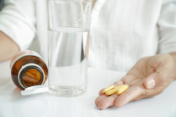 Woman taking vitamins, drinks supplements.
