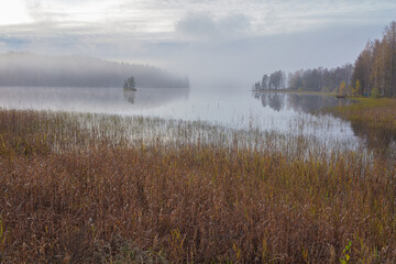 Autumn, foggy morning, over the lake, in the distance you can see a small island. Finland, Scandinavian nature.