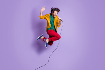 Photo portrait full body view of guy shouting singing into mic jumping up isolated on vivid purple...