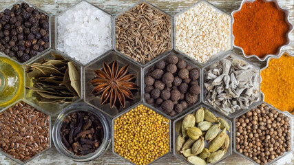 Spices in hexagonal jars on a wooden surface