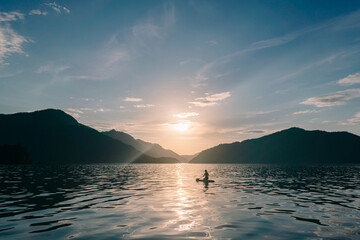 Girl at sunset on the lake on a stand-up paddle board in Altai