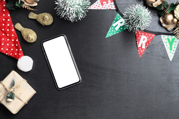 Mockup blank white screen smartphone on black desk table background for Christmas and New Year party background, Flat lay top view with copy space for your Merry Christmas and Happy New year artwork.