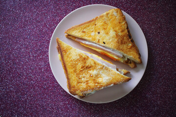 French Croque-madame sandwich on a pink plate and raspberry background
