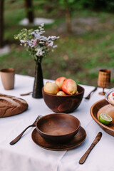 Pears lie in a wooden plate on a wooden table near to glasses and other utensils