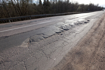 Bad quality road with potholes. Hole in asphalt. Pit, unsafe, hole road. Transportation