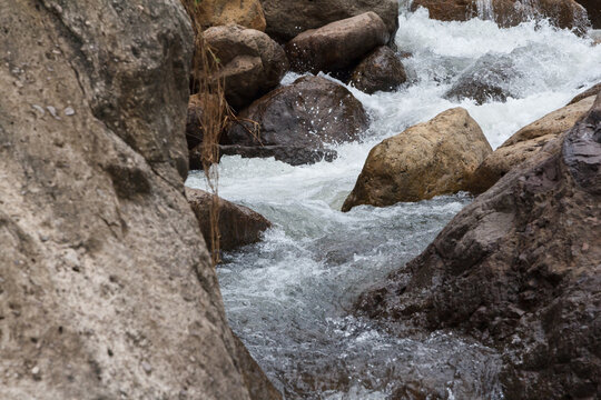 Close up of a little cascade falls of water over mountain river rocks.