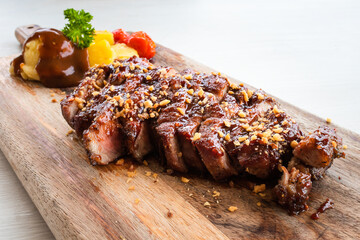 Grilled pork steak with tomato, pineapple and mashed potato on wood plate close-up.
