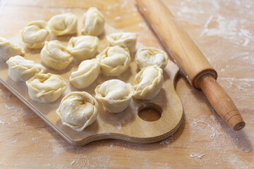 Fototapeta na wymiar Closeup on semi-finished pelmeni dumplings on the wooden board.