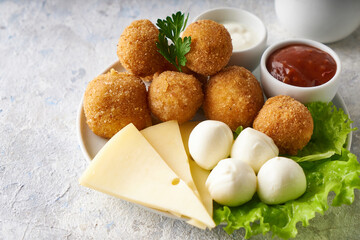 cheese balls, appetizer with herbs and sauces in a plate on a gray table