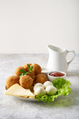 cheese balls, appetizer with herbs and sauces in a plate on a gray table