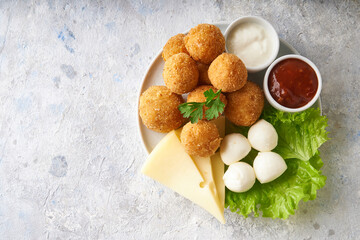 Obraz na płótnie Canvas cheese balls, appetizer with herbs and sauces in a plate on a gray table
