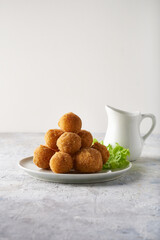 cheese balls, appetizer with herbs and sauces in a plate on a gray table