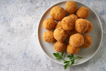 Fried cheese balls, appetizer with herbs and sauces in a plate on a gray table Copyspace