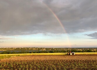 Tractor in the field,above it a rainbow.