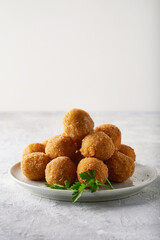 Fried cheese balls, appetizer with herbs and sauces in a plate on a gray table Copyspace