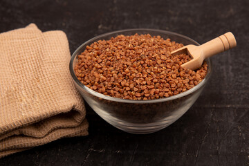 Dry buckwheat in a transparent bowl with wooden spoon rustic style