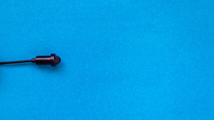 Small size audio microphone on a blue background. Copy space.