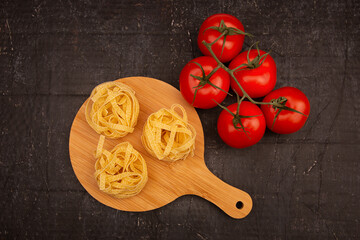 Raw Pasta with tomatoes on a wooden chopping Board