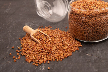 Dry buckwheat in a glass jar and wooden spoon
