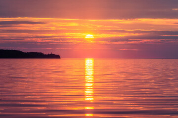 A sunny path from the setting sun on the calm water.