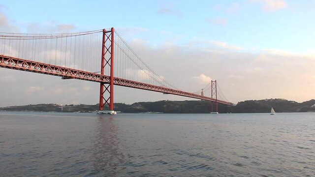 Sailboat on Tagus river with 25th of April Bridge on background in Lisbon, Portugal. Tourist attraction, vacation destination concepts