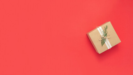 Christmas craft wrapped gift flat lay on red background with copy space. New Year present concept.