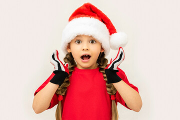Little girl in a Christmas hat on a white isolated background.