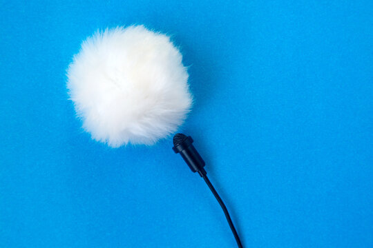 Lavalier small microphone and wind protection blue background.