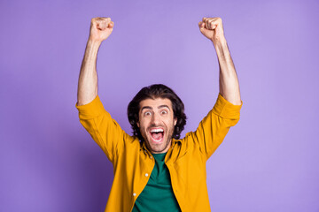 Fototapeta premium Photo of young crazy happy triumphant ecstatic male man guy raise fists shout isolated on purple color background
