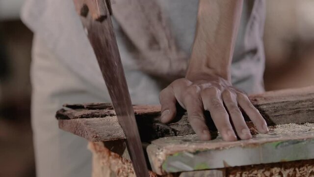 close up of a worker sawing wood while working at the workshop