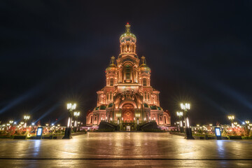Fototapeta na wymiar Front view from of the Main Cathedral of the Russian Armed Forces in honor of the Resurrection of Christ with bell tower at Patriot theme park in Kubinka illuminated in gold color in the dusk..