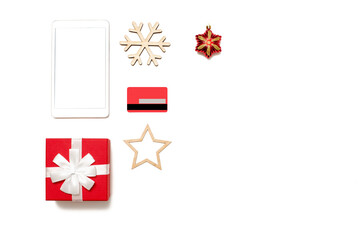 Digital tablet with copy space top view on white table, credit card, present box and christmas toys
