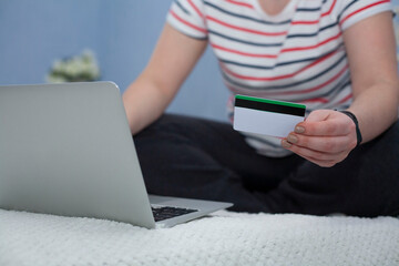 Naklejka premium A woman orders gifts over the Internet. A woman's hand holds a credit card. Online ordering. Online shopping