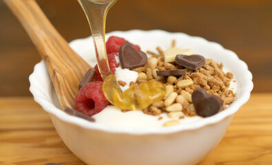 white yogurt with honet, cereal grain and fresh raspberries