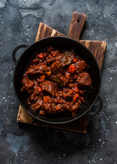 Classic beef stew in a pan on a dark background, top view. Delicious comfort homemade food