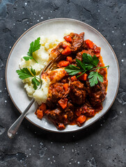 Classic beef stew with mashed potatoes on a dark background, top view. Delicious comfort homemade food