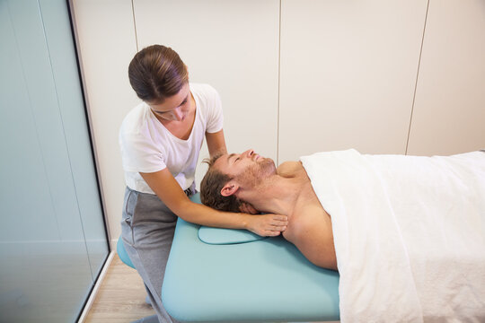 Female physiotherapist giving head massage to male patient