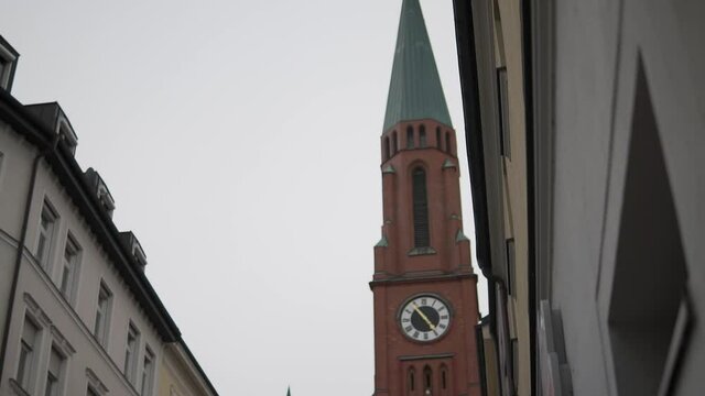 St Johann Baptist Church, Landmark of East Munich, Germany. Cinematic Slow Motion Reveal of Clok Tower Under Cloudy Sky
