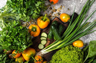 Vegetables and greens with chopping board on the table. Top view.