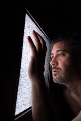 Hombre mira la tv sin conexión apoyando su mano
