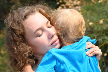 mom holds her little baby boy in her arms, to feel sorry, the child hugs his mother and snuggles up to her