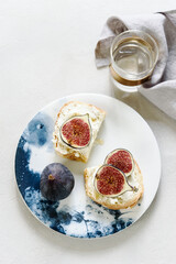 Obraz na płótnie Canvas Two Sandwich with Ricotta and fresh Figs sprinkled honey on plate on grey concrete background. Simple healthy breakfast