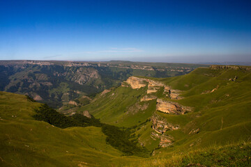 Beautiful alpine meadow on a sunny day with a gorge. Blue sky