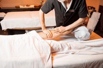 Professional therapist doing a deep massage to a male client at Spa salon. working on the lower body