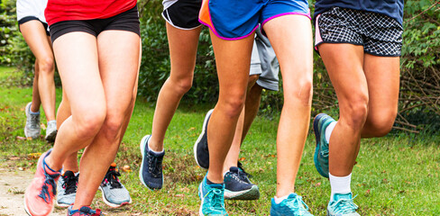 Legs of a group of runners running together in a park