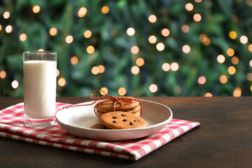Christmas cookies and milk for Santa near Xmas tree. Close up. Happy holidays.