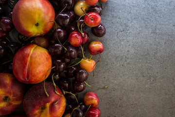 Juicy fruits and berries on a table. Dark grey textured background with copy space. Healthy eating concept. Vibrant colors of fresh fruits. 
